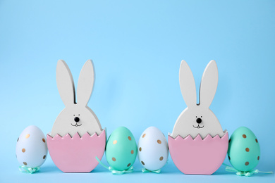 Photo of Easter bunnies and painted eggs on light blue background