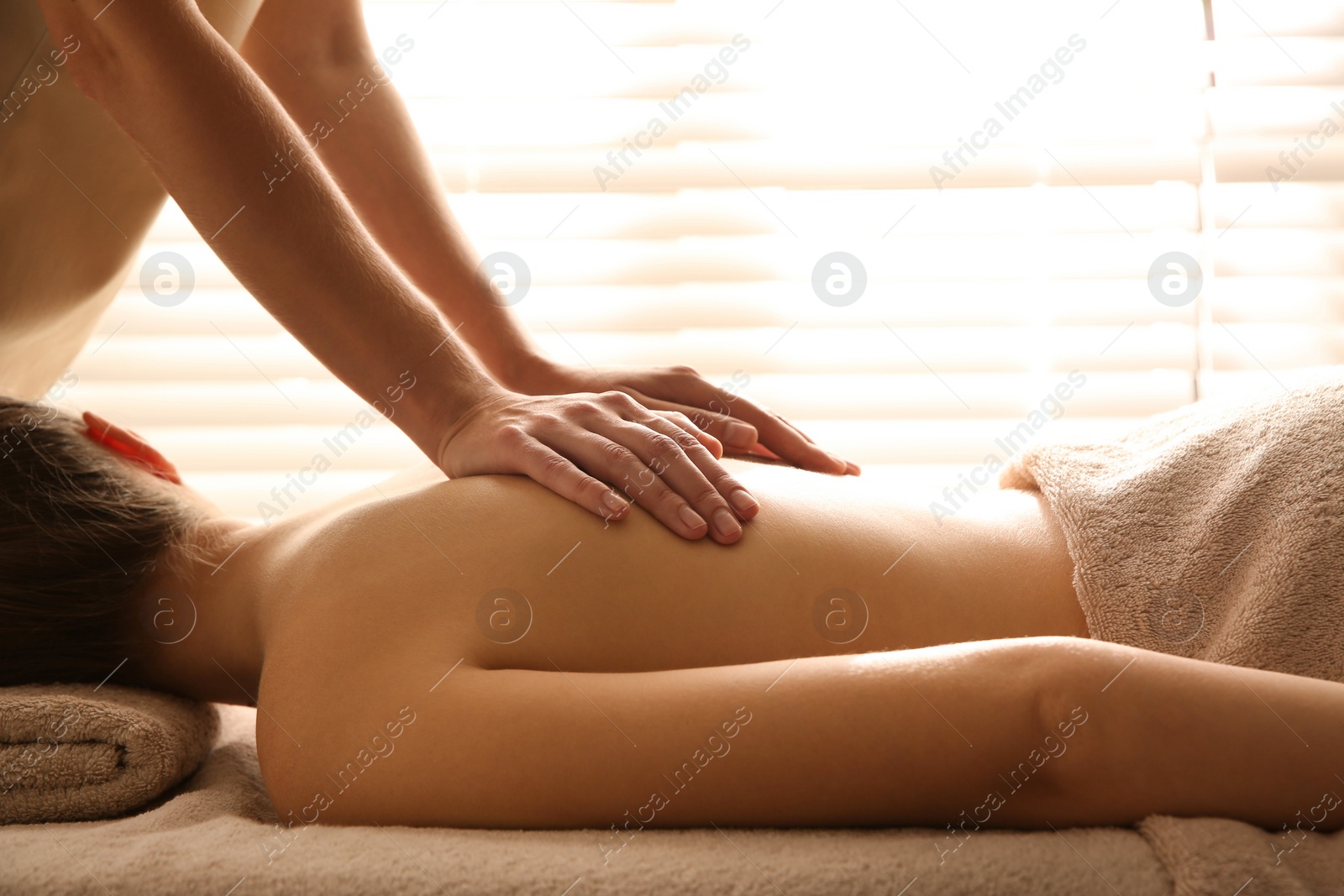 Photo of Young woman receiving back massage in spa salon