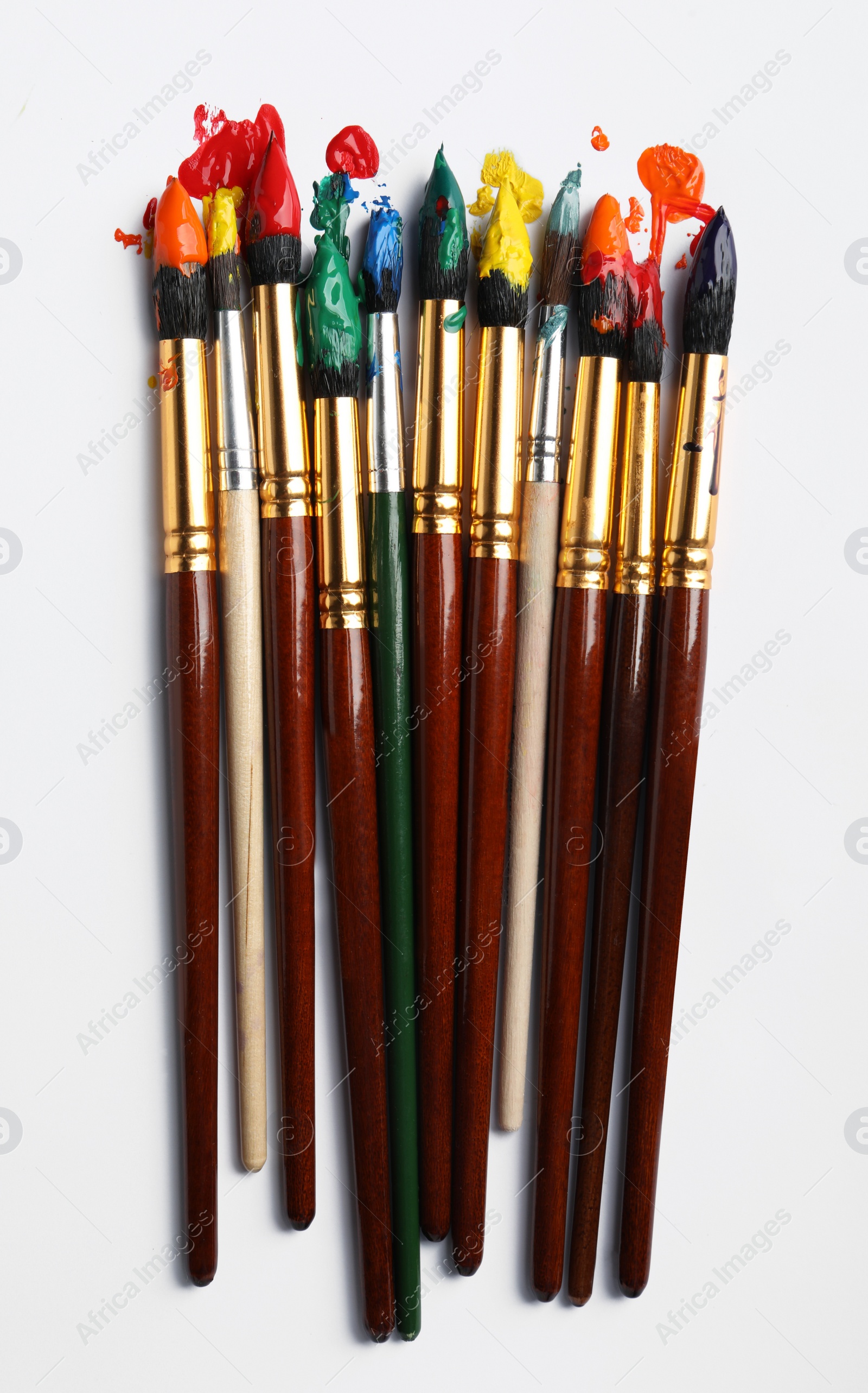 Photo of Brushes with colorful paints on white background, flat lay