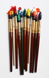 Photo of Brushes with colorful paints on white background, flat lay