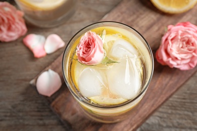 Photo of Delicious refreshing drink with lemon and rose on wooden table, top view