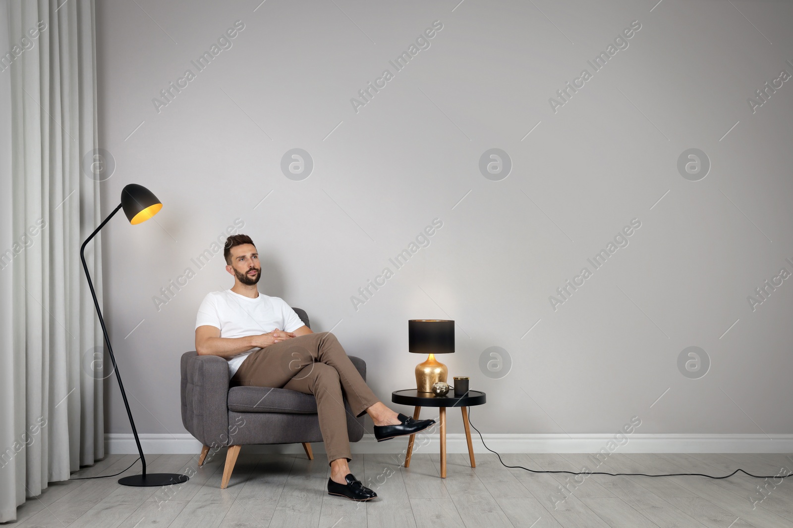 Photo of Man sitting in armchair near gray wall, space for text