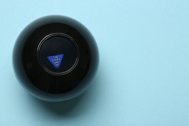 Photo of Magic eight ball with prediction The Stars Say No on light blue background, top view. Space for text