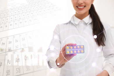 Professional pharmacist with pills and periodic table, closeup