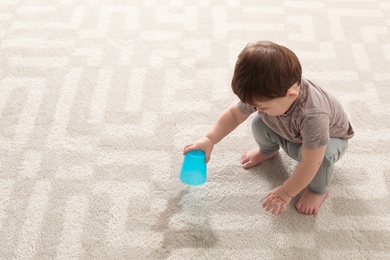 Photo of Baby sitting on carpet with empty glass