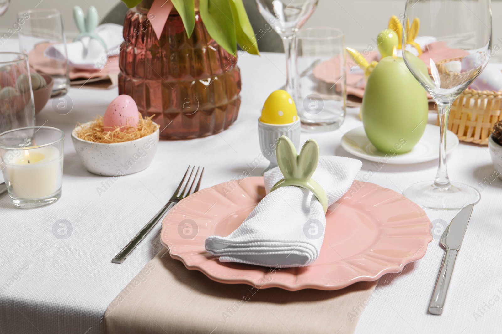 Photo of Festive table setting with napkin ring in shape of bunny ears. Easter celebration