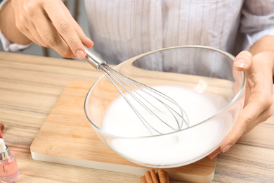 Photo of Woman making natural handmade soap at wooden table, closeup