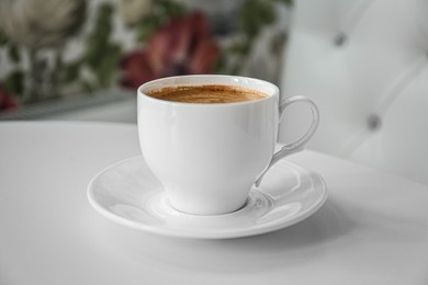 Photo of Cup of delicious aromatic coffee on white table indoors, closeup