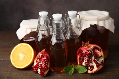 Photo of Tasty kombucha, mint and fresh fruits on wooden table