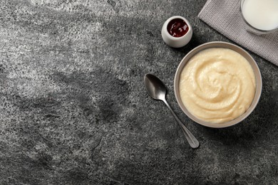 Photo of Bowl with delicious semolina pudding on grey table, flat lay. Space for text