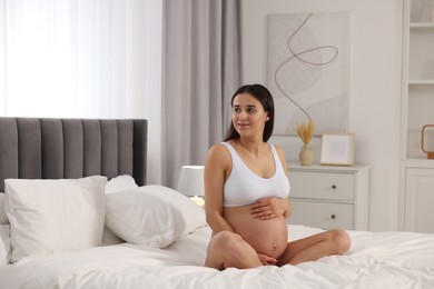 Beautiful pregnant woman in stylish comfortable underwear on bed at home