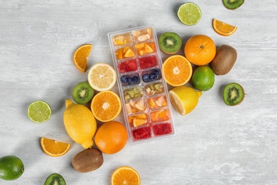 Photo of Flat lay composition with ice cube tray and fresh fruits on light background