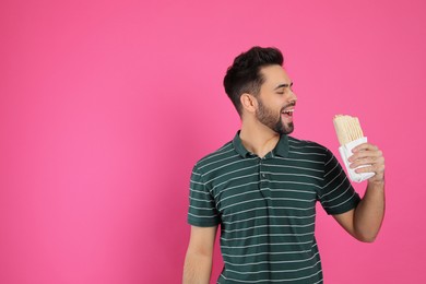 Photo of Young man eating tasty shawarma on pink background. Space for text