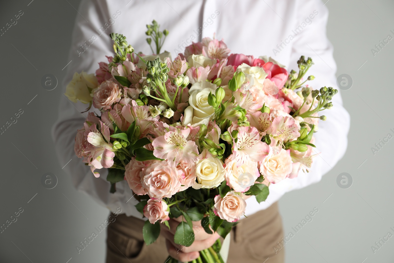 Photo of Man with beautiful bouquet of flowers on grey background, closeup