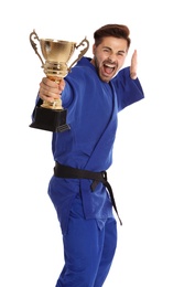 Photo of Portrait of young emotional man in blue kimono with gold trophy cup on white background