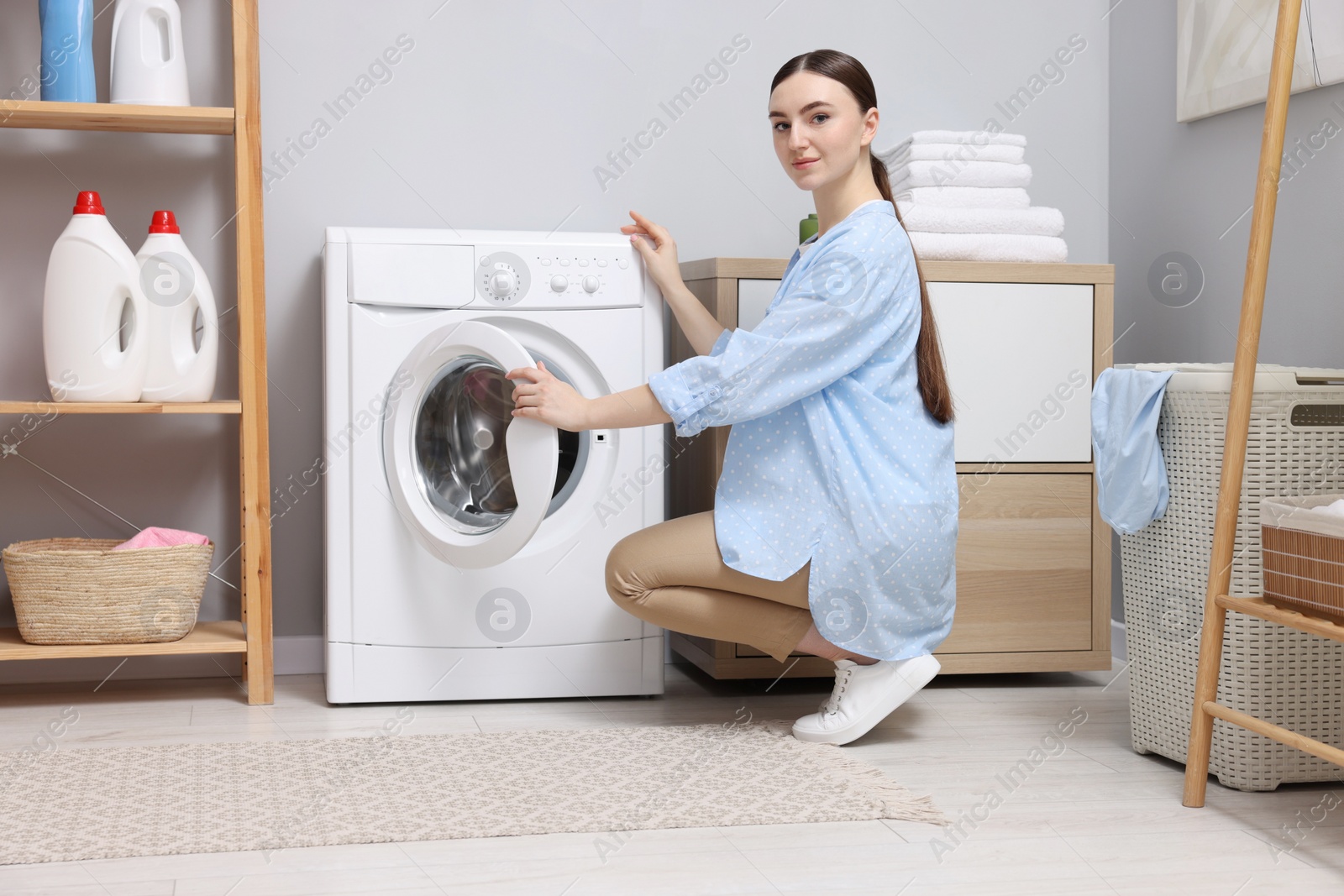 Photo of Beautiful woman near washing machine in laundry room