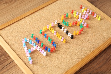 Cork board with word Autism made of colorful pins on wooden table, closeup