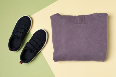 Violet garment and sport shoes on color background, flat lay