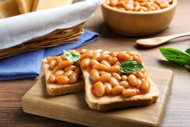 Photo of Toasts with delicious canned beans on wooden table