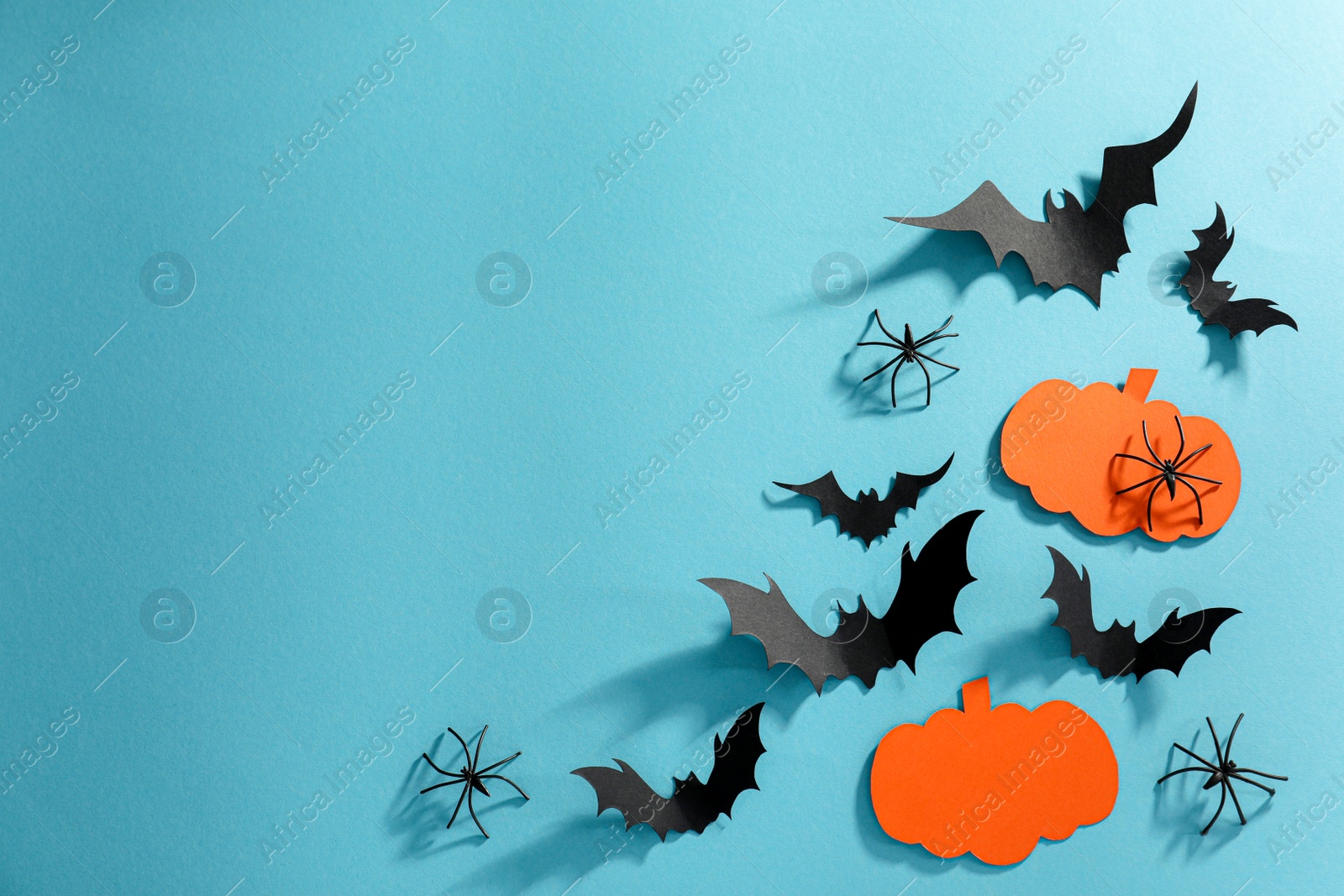 Photo of Flat lay composition with paper bats, pumpkins and spiders on light blue background, space for text. Halloween decor