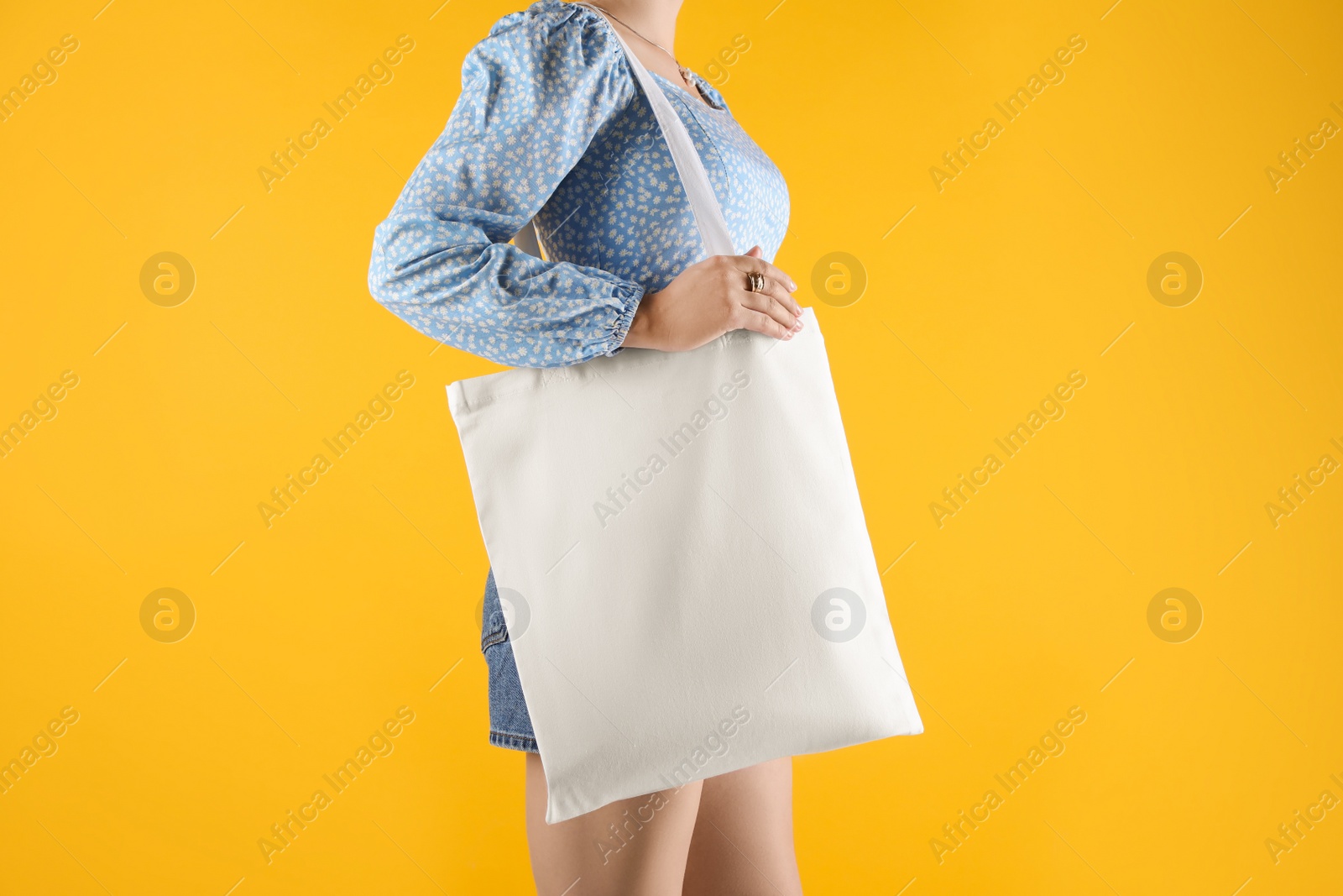 Photo of Woman with white textile bag on orange background, closeup. Space for design