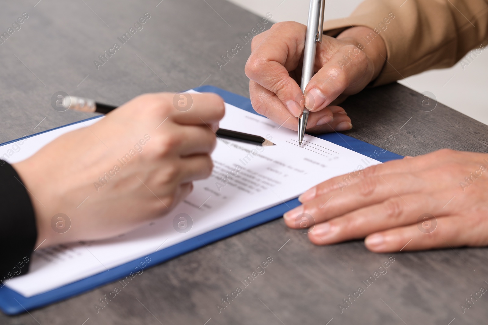 Photo of Manager showing client where she must to mark signature at dark table, closeup