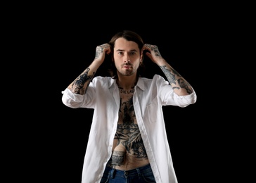 Photo of Young man with tattoos on body against black background