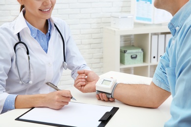 Photo of Doctor checking mature man's pulse with medical device in hospital, closeup