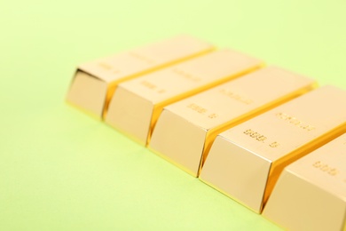 Photo of Shiny gold bars on color background, closeup