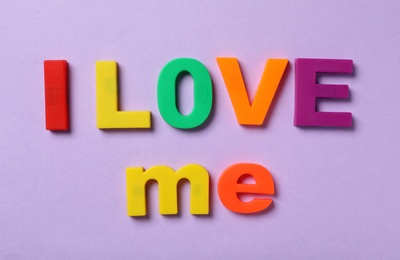 Phrase I Love Me made of colorful letters on violet background, flat lay