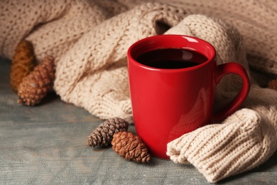 Composition with cup of hot cozy drink and autumn sweater on table. Space for text