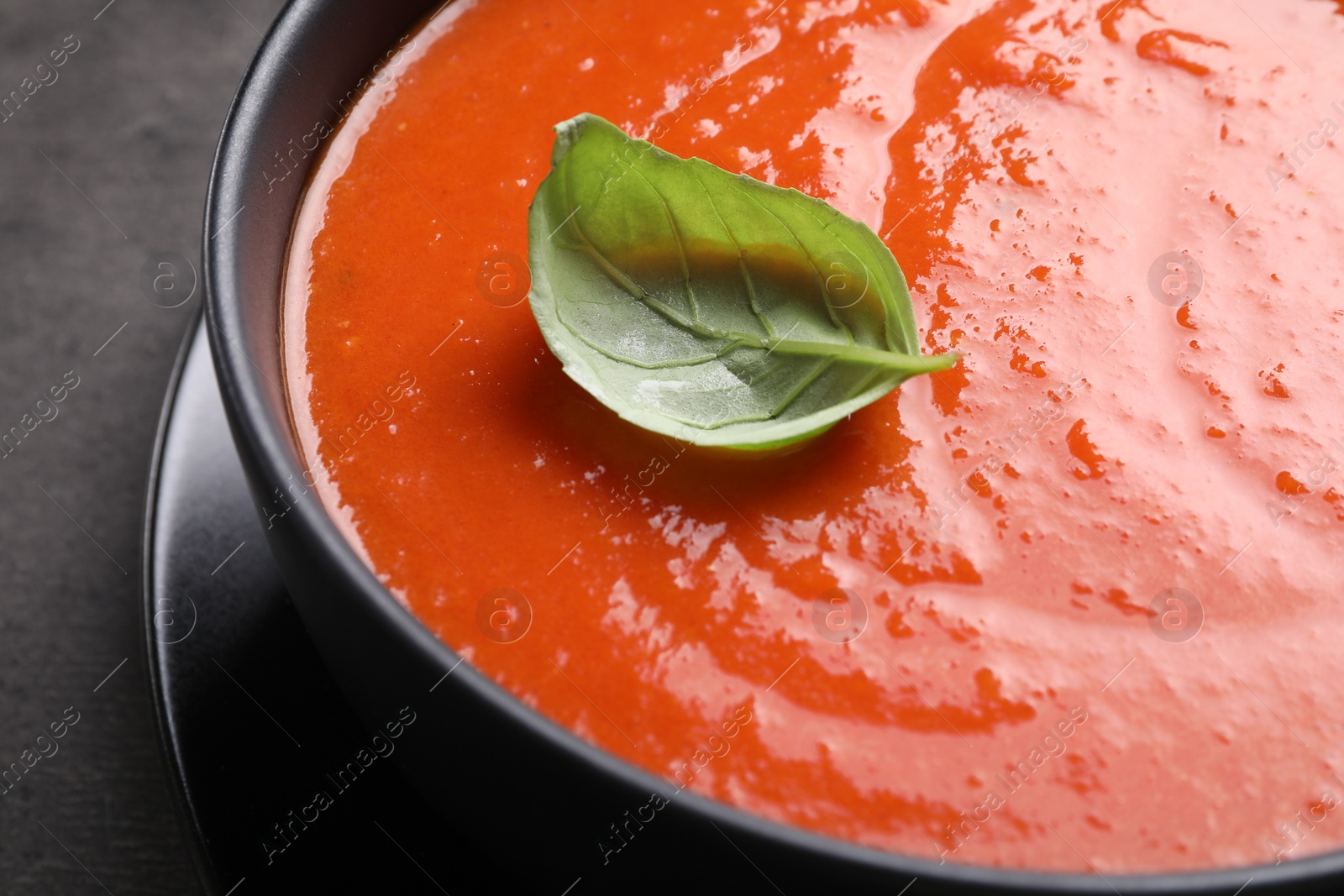 Photo of Delicious tomato cream soup in bowl on grey table, closeup