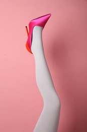 Photo of Woman wearing white tights and high heel shoe on pink background, closeup