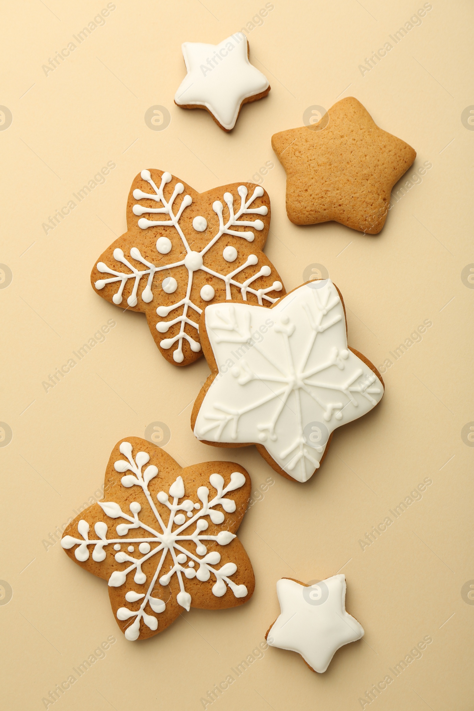 Photo of Tasty Christmas cookies with icing on beige background, flat lay