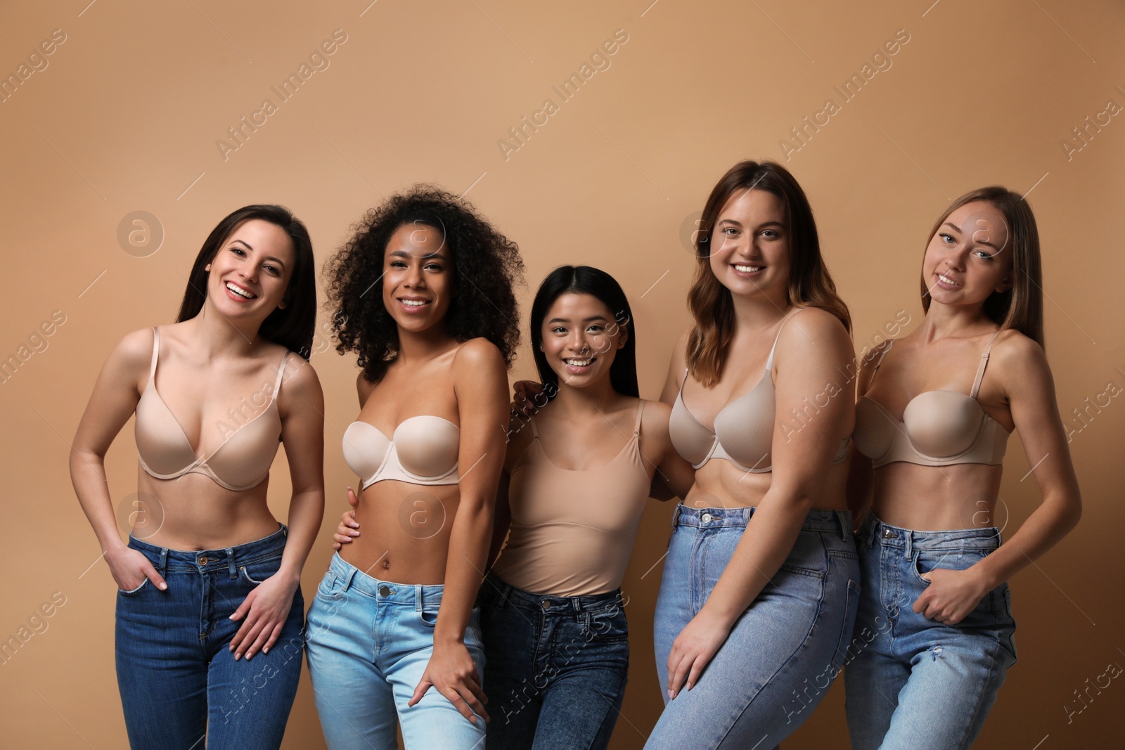 Photo of Group of women with different body types in jeans and underwear on beige background