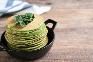 Photo of Tasty spinach pancakes on wooden table, closeup. Space for text