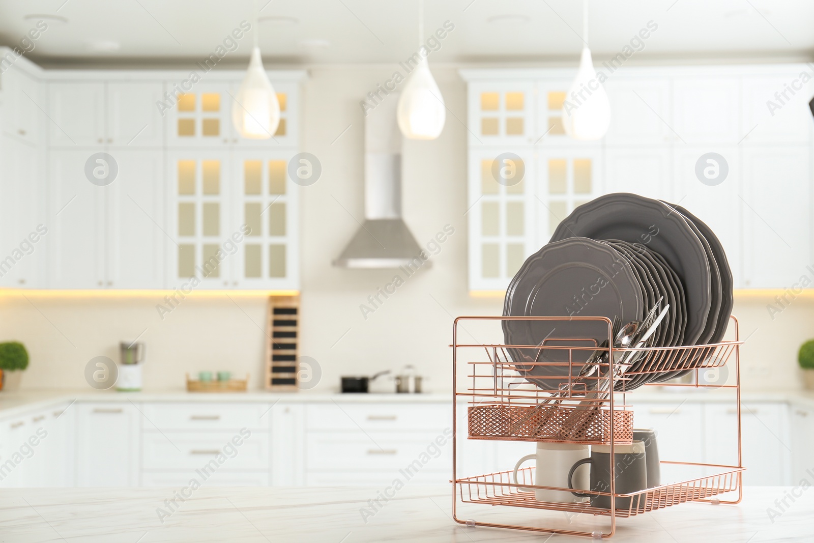 Photo of Drying rack with clean dishes on table in kitchen. Space for text