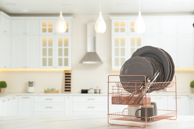 Drying rack with clean dishes on table in kitchen. Space for text