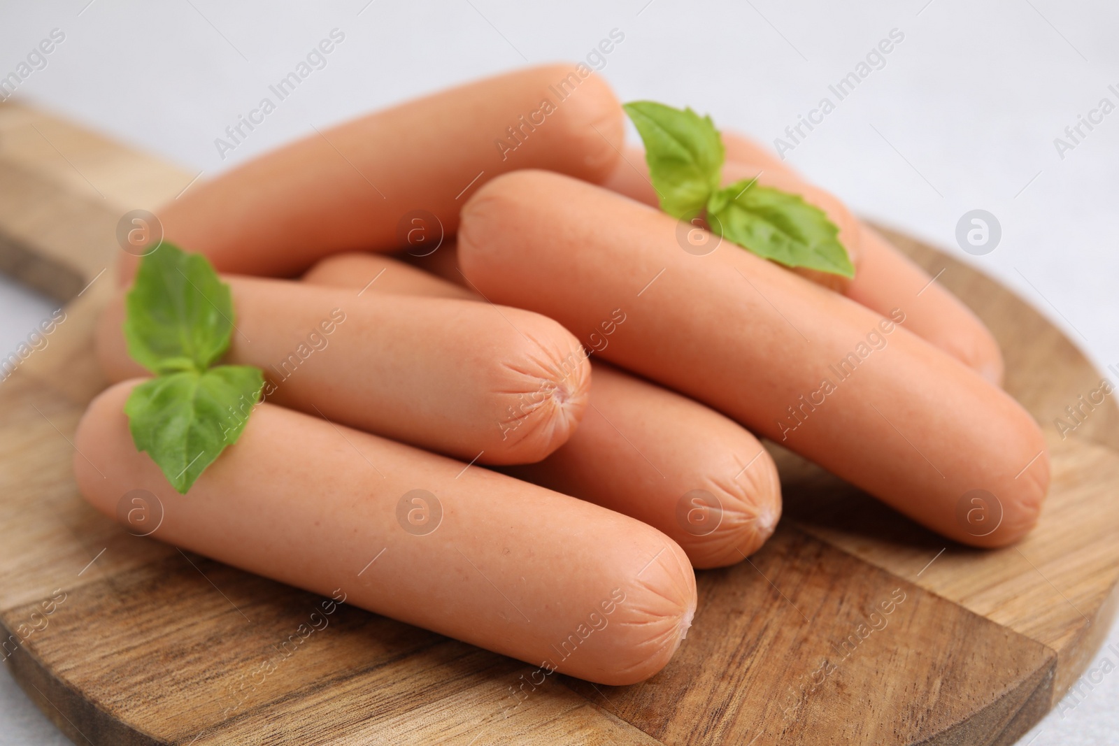 Photo of Delicious boiled sausages and basil on table, closeup