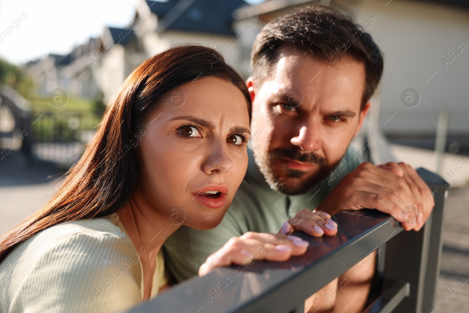 Photo of Concept of private life. Curious couple spying on neighbours over fence outdoors