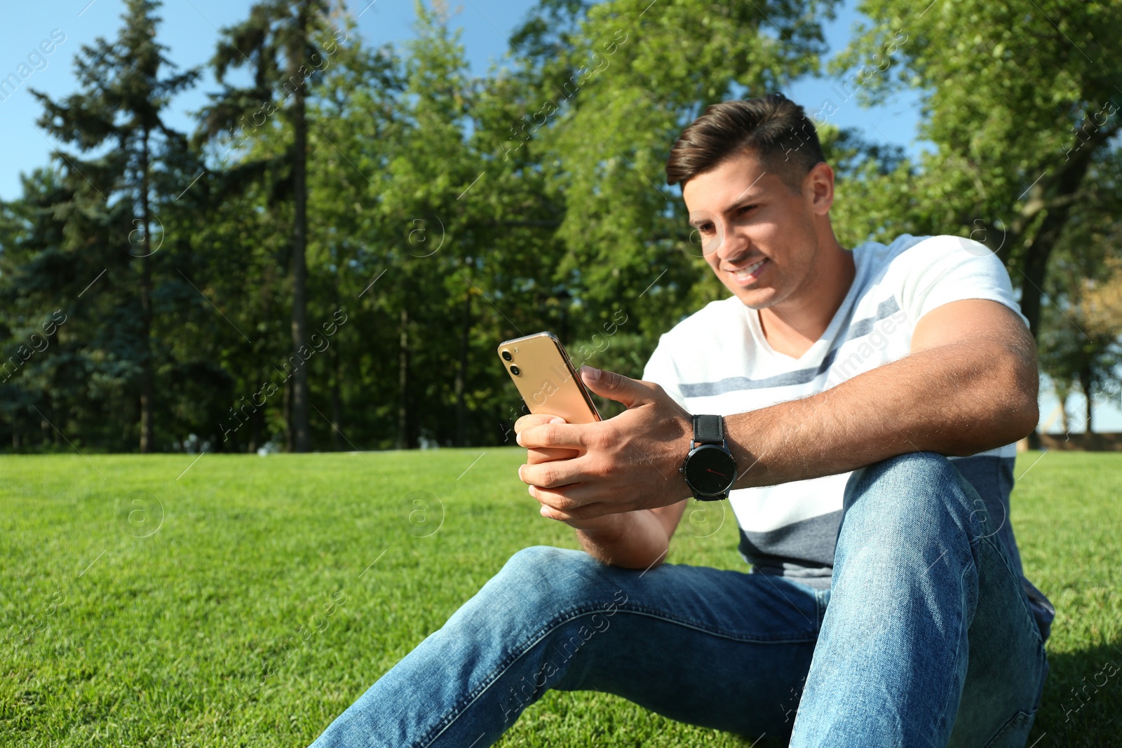 Photo of Handsome man using modern mobile phone in park