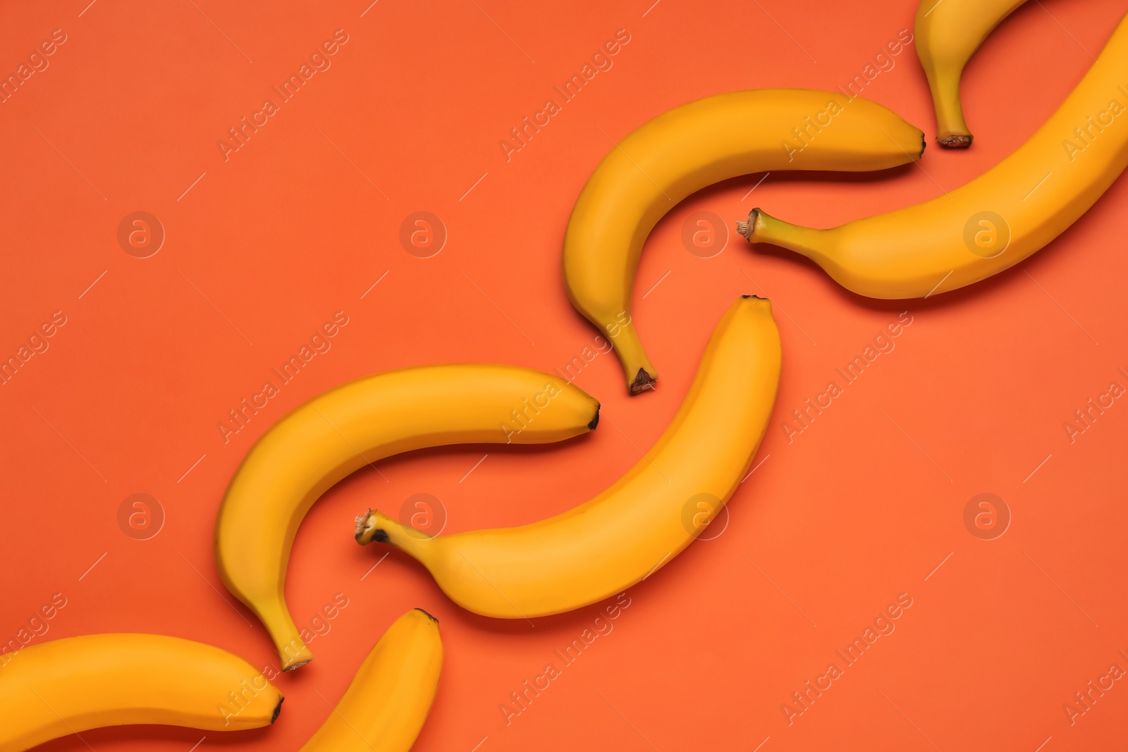 Photo of Ripe yellow bananas on coral background, flat lay