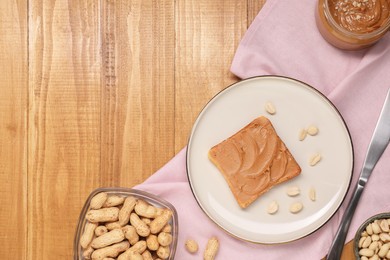 Photo of Toast with tasty nut butter and peanuts on wooden table, flat lay. Space for text
