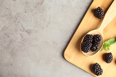 Flat lay composition of ripe blackberries on grey table, space for text