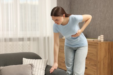 Photo of Woman having heart attack near sofa at home