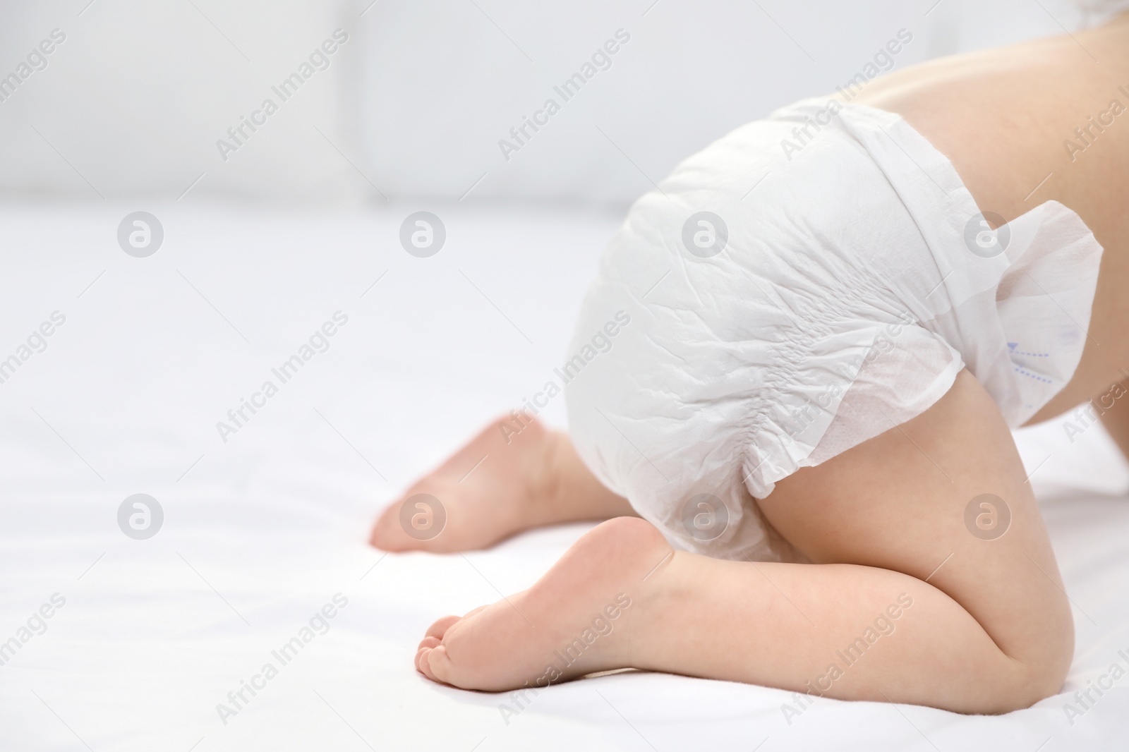 Photo of Cute little baby in diaper on bed, closeup. Space for text