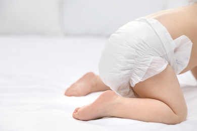 Photo of Cute little baby in diaper on bed, closeup. Space for text
