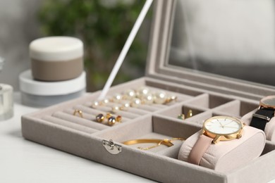 Jewelry box with many different accessories on white wooden table, closeup