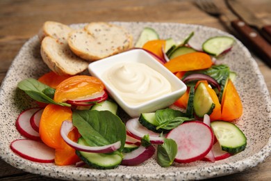 Photo of Plate of delicious vegetable salad with mayonnaise and croutons on table, closeup