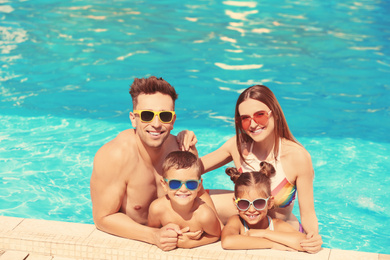 Image of Happy family in swimming pool on sunny day
